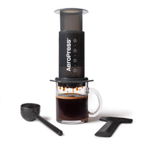 AeroPress with included accessories — scoop, stirrer, filter cap and 100 paper filters. Please note - no glass cup included.