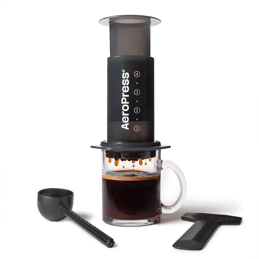 AeroPress with included accessories — scoop, stirrer, filter cap and 100 paper filters. Please note - no glass cup included.