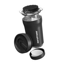 Black AeroPress Go Plus coffee maker with a clear chamber and perforated cap, shown alongside its lid and a filter holder containing circular paper filters.