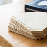 Clever Dripper Filter Papers - stack of filter papers on a wooden table with blue packaging box in the background