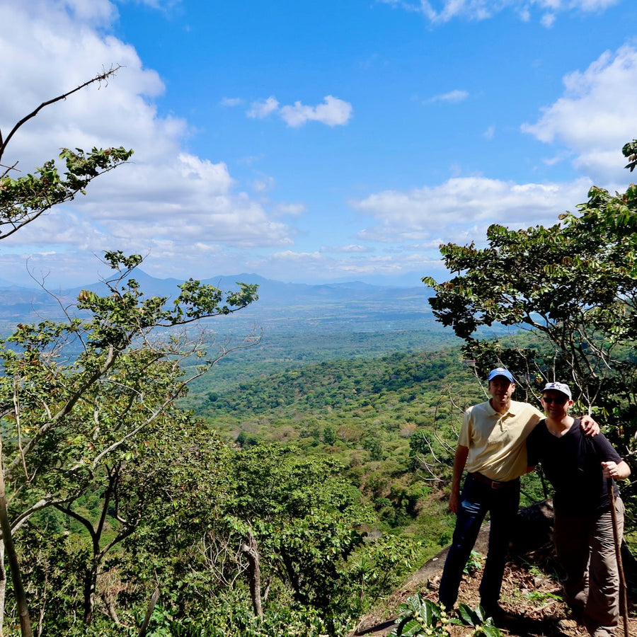 Alejandro Martinez and OCR Green Buyer Roland Glew at Finca Argentina in El Salvador with the Apaneca-Ilamtepec mountain range in the distance