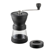 Black manual coffee grinder with clear container on a white background