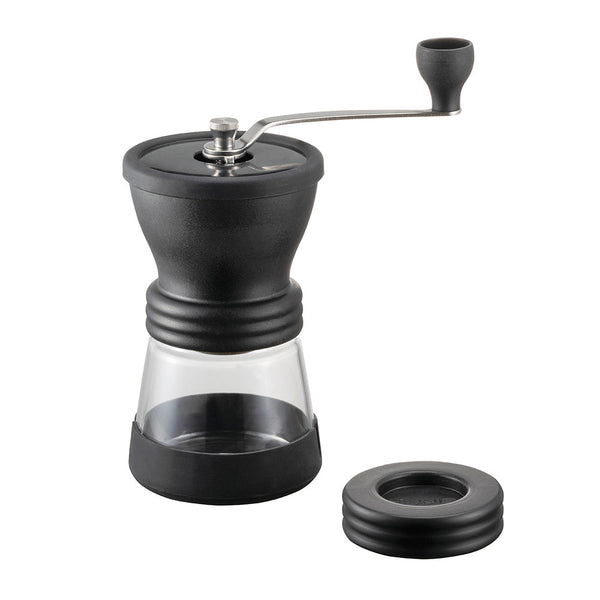 Black manual coffee grinder with clear container on a white background