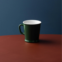 Acme Union Mug 230ml in Kawakawa green, styled on a terracotta surface against a blue wall