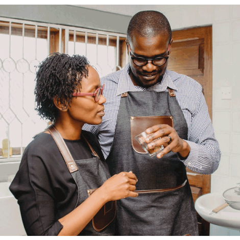 Mama Aya looks at a glass containing coffee being held by a man
